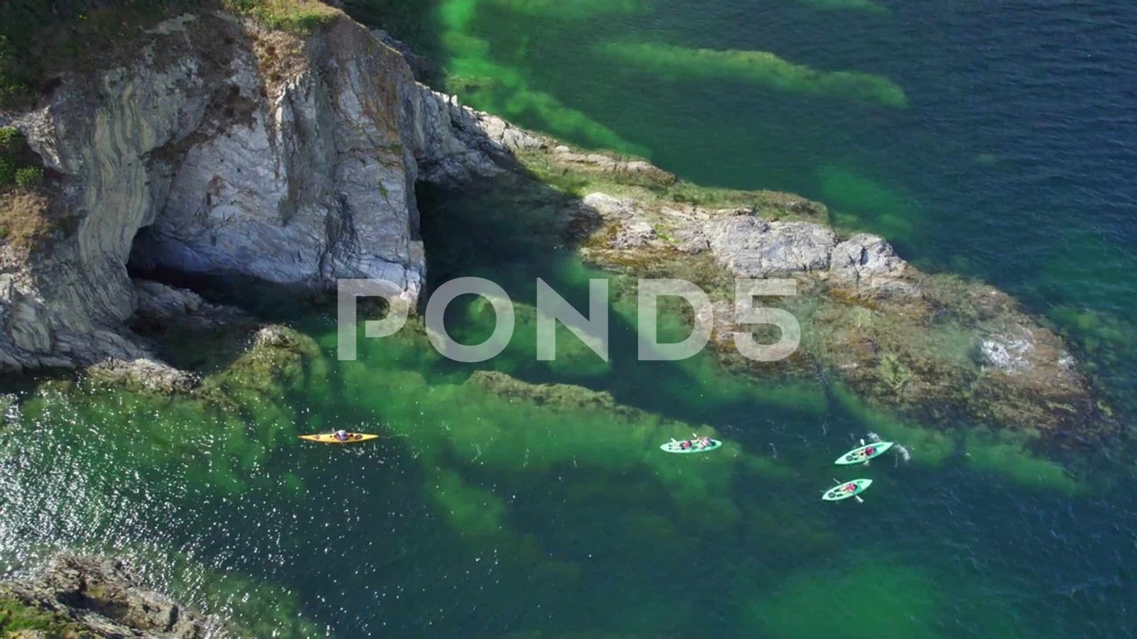 Aerial shot of rugged rocky coastline with kayakers, Cornwall, UK